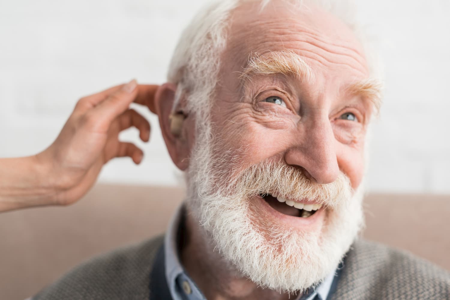 Woman hand helping grey haired man, wearing hearing aid