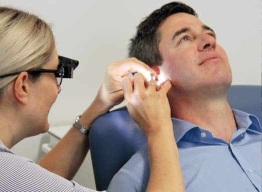 nurse removing earwax from patient's ear