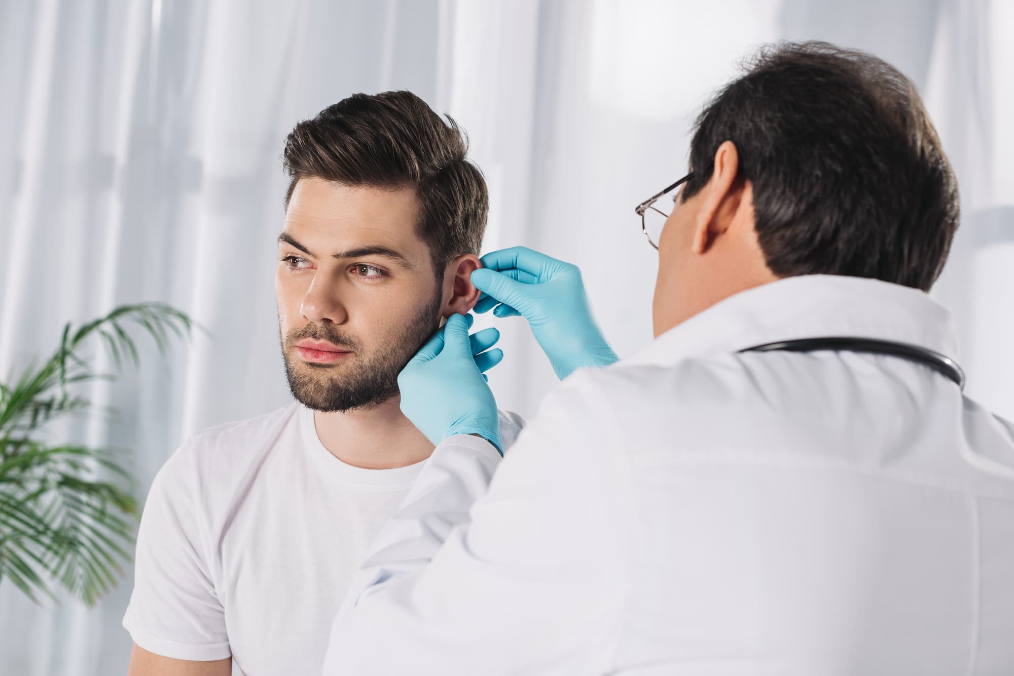 Doctor examining male patient ear