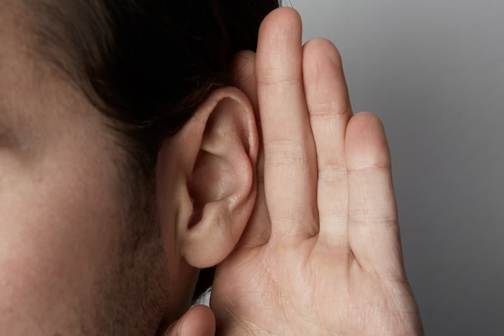 man holds his hand near his ear