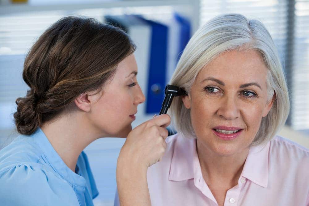 doctor examining patients ear with otoscope