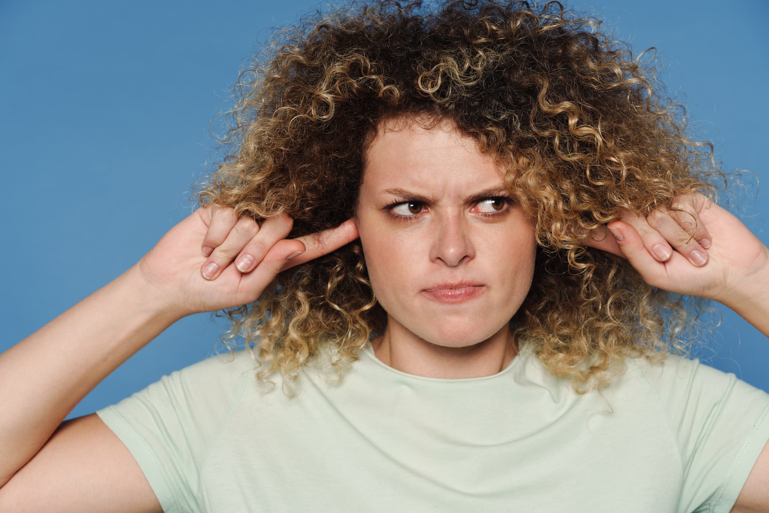 Lady with frizzy hair with fingers in her ears
