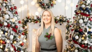 Lisa Hellwege smiling in festive Christmas setting with decorated trees and lights