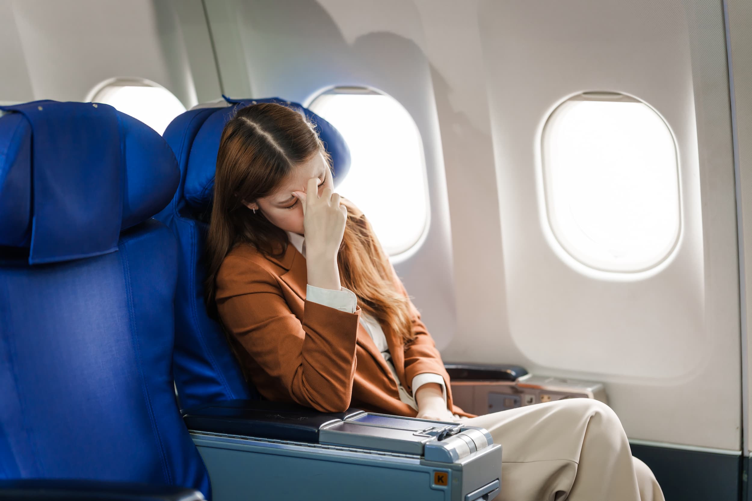 Woman holding head from blocked ears on plane