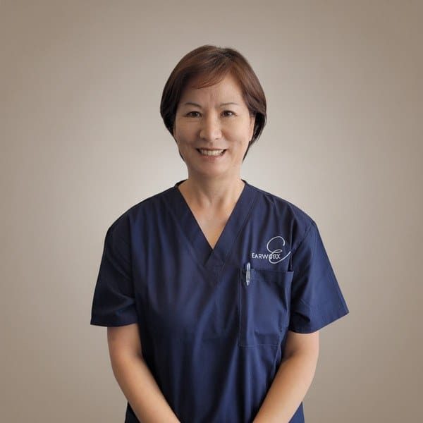 Young Mi Sun, Earworx Registered Nurse, smiling in navy Earworx scrubs against a neutral background